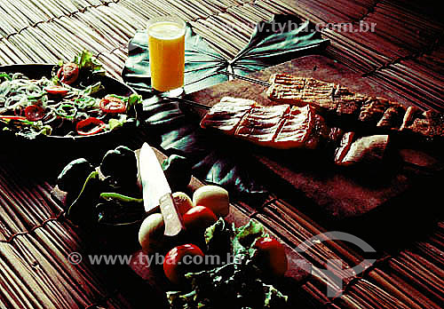  Culinária - costeleta de porco, copo com suco de laranja, tomates, cebolas e salada verde. 