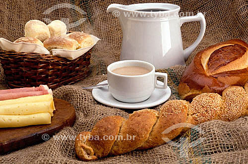 Mesa de café da manhã: cesta com pães, queijo, xícara de café com leite e bule de café. 