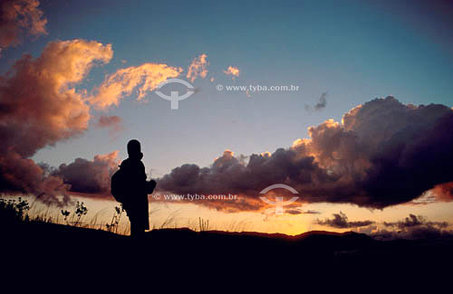  Silhueta de homem com mochila fazendo trekking ao pôr-do-sol - Brasil 