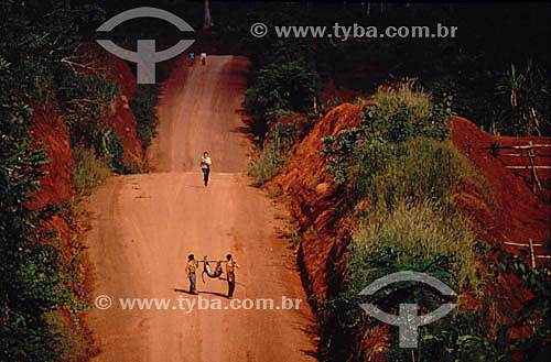  Rodovia Transamazônica, com colonos passando e dois deles dividindo uma caça no ombro - Amazônia - Brasil 