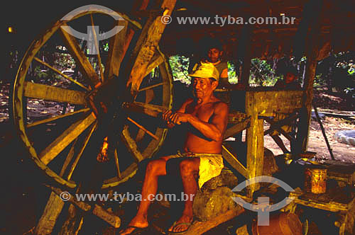  Pequeno trabalhador rural usando roda movida manualmente para moer mandioca - Sr. Ramiro, S. José e Bruno - Amazônia - Brasil  - Amazonas - Brasil