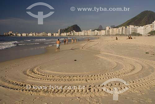  Pessoas caminhando na praia de Copacabana ao amanhecer com rastro de trator em primeiro plano - Rio de Janeiro - RJ - Brasil  - Rio de Janeiro - Rio de Janeiro - Brasil