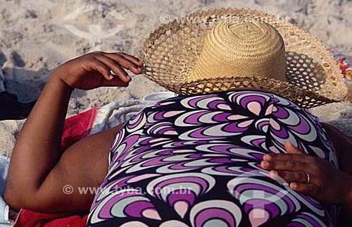  Mulher deitada na praia com chapéu 