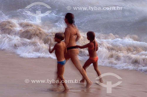  Família - mãe e filhos caminhando na praia 