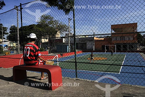  Assunto: Jovem sentado em banco vermelho vestido com a camisa do Flamengo assistindo jogo de bola na quadra.
Local: Praça Gilson Mendonça - Carapina Grande / Serra - ES
Data: Março de 2008 