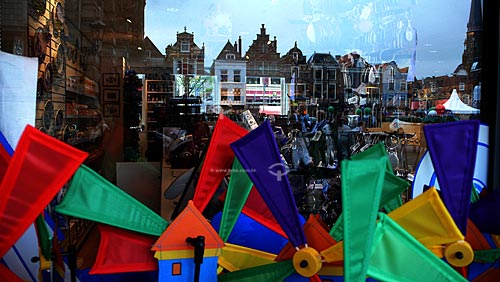  Vitrine de uma loja refletindo os prédios da cidade de Delft com moinhos de brinquedo à venda em primeiro plano - Delft - Holanda  