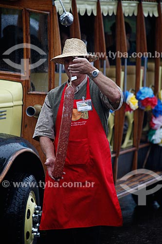  Assunto: Homem segurando salame em frente ao Ônibus da Feira da colônia alemã / Local: Gramado - Rio Grande do Sul (RS) - Brasil / Data: 02/2012 