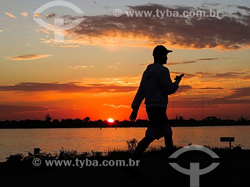  Homem caminhando às marges da Beira do Lago Guaíba durante o pôr do sol  - Porto Alegre - Rio Grande do Sul (RS) - Brasil
