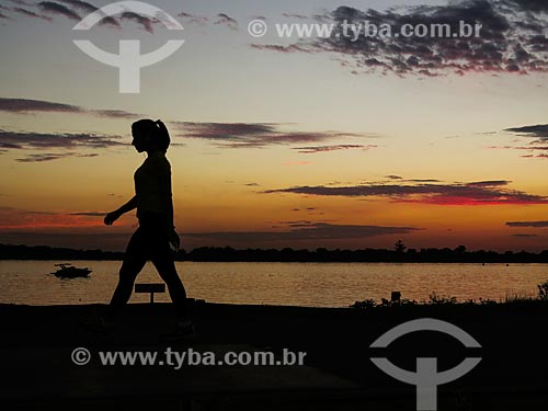  Mulher caminhando às marges da Beira do Lago Guaíba durante o pôr do sol  - Porto Alegre - Rio Grande do Sul (RS) - Brasil