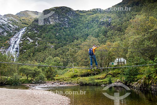  Turista atravessando ponte sobre o rio na trilha em Fort William - próximo à região de Glen coe  - Fort William - Highland - Escócia