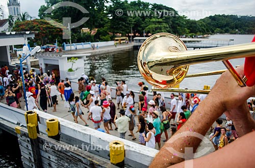  Pessoa tocando trombone e foliões desembarcando na Ilha de Paquetá para bloco de carnaval  - Rio de Janeiro - Rio de Janeiro (RJ) - Brasil