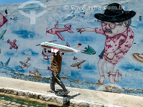  Artesão Vantuir com avião de brinquedo e muro com grafite ao fundo  - Nova Olinda - Ceará (CE) - Brasil