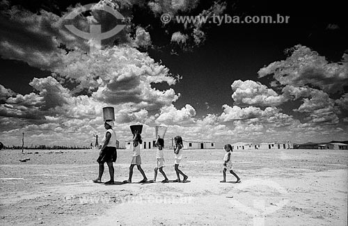  Mulher e crianças carregando lata dágua na cabeça  - Canudos - Bahia (BA) - Brasil
