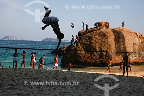  Praticante de slackline na Praia do Vidigal com banhista pulando no mar das pedras ao fundo  - Rio de Janeiro - Rio de Janeiro (RJ) - Brasil