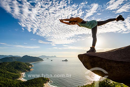 Mulher praticando Yoga - movimento virabhadrasana (guerreiro) - na Pedra do Telégrafo no Morro de Guaratiba  - Rio de Janeiro - Rio de Janeiro (RJ) - Brasil