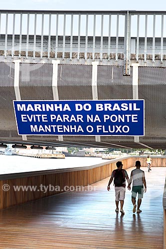  Pessoas caminhando na Orla Prefeito Luiz Paulo Conde com placa com os dizeres: Marinha do Brasil: evite parar na ponte mantenha o fluxo  - Rio de Janeiro - Rio de Janeiro (RJ) - Brasil