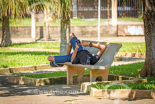  Adolescente usando celular deitado em banco de praça  - Guarani - Minas Gerais (MG) - Brasil