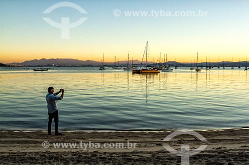  Homem fotografando a orla da Praia de Santo Antônio de Lisboa durante o pôr do sol  - Florianópolis - Santa Catarina (SC) - Brasil