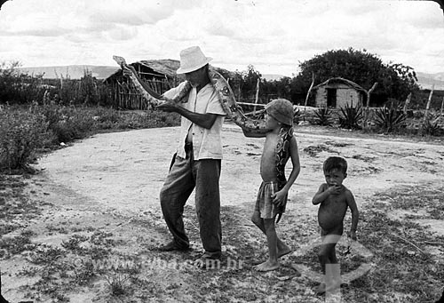  Homem e menino carregando cobra durante o período de seca - Década de 80  - Ceará (CE) - Brasil