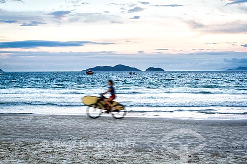  Surfista com prancha de surf em bicicleta na orla da Praia do Pântano do Sul  - Florianópolis - Santa Catarina (SC) - Brasil