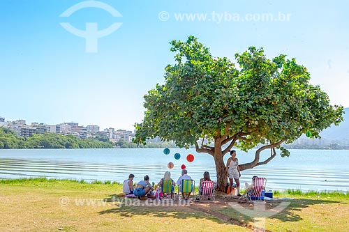 Pessoas protegendo-se do sol em sombra de árvore durante festa de aniversário às margens da Lagoa Rodrigo de Freitas  - Rio de Janeiro - Rio de Janeiro (RJ) - Brasil