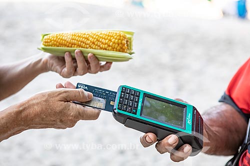  Detalhe de vendedor ambulante de milho cozido usando máquina de cartão na orla da Praia de Copacabana  - Rio de Janeiro - Rio de Janeiro (RJ) - Brasil