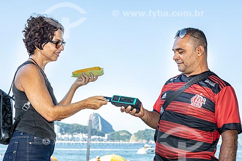  Vendedor ambulante de milho cozido usando máquina de cartão na orla da Praia de Copacabana  - Rio de Janeiro - Rio de Janeiro (RJ) - Brasil