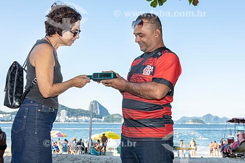  Vendedor ambulante de milho cozido usando máquina de cartão na orla da Praia de Copacabana  - Rio de Janeiro - Rio de Janeiro (RJ) - Brasil