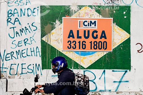  Motoqueiro passa em frente a placa sugerindo que o Brasil está para alugar - Crise do Coronavírus  - Porto Alegre - Rio Grande do Sul (RS) - Brasil