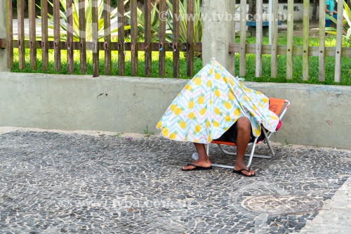 Homem debaixo de barraca de praia semi fechada no calçadão do Arpoador - Rio de Janeiro - Rio de Janeiro (RJ) - Brasil