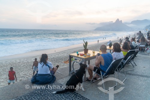 Pessoas em mesas de bar ao entardecer na praia do Arpoador com o Morro Dois Irmãos ao fundo - Rio de Janeiro - Rio de Janeiro (RJ) - Brasil