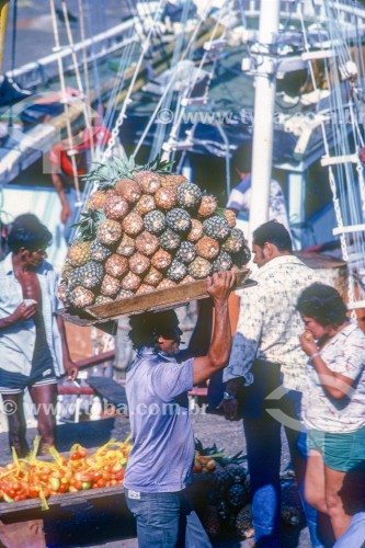 Homem carregando abacaxis no Mercado Ver-o-peso - Anos 80 - Belém - Pará (PA) - Brasil