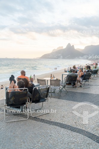 Pessoas sentadas em mesas do quiosque Alalaô no calçadão de Ipanema para assistir ao por-do-sol - Rio de Janeiro - Rio de Janeiro (RJ) - Brasil