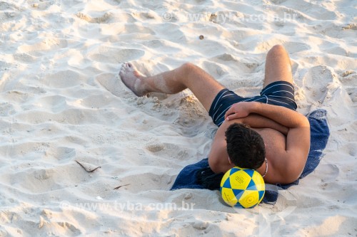 Jovem deitado na areia com cabeça apoiada sobre uma bola de futebol - Rio de Janeiro - Rio de Janeiro (RJ) - Brasil
