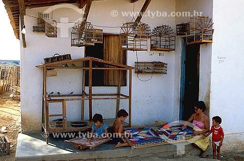  Craftwork - Embroidery - Mother and children working on the fabric - House with several little bird cages on the wall  - Jaguari city - Brazil