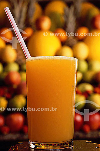  A glass of orange juice and fruits in the background 