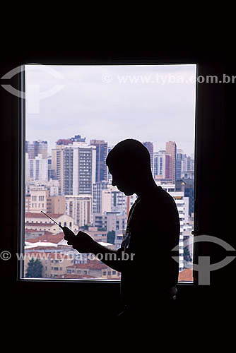  Telecommunications -  Silhouette of a man holding a mobile phone - Curitiba city - Parana state - Brazil 