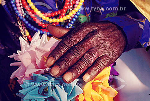  Detail of a black hand with flowers and colored necklaces 