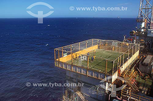  Workers playing soccer on a soccer field at a petroleum platform.  