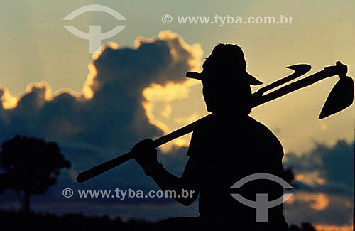  Silhouette of a rural worker holding the scythe and the hoe - Amazonian - Brazil 