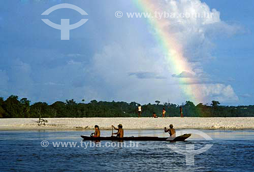 Indians crossing Rio Negro river in boat with rainbow on the background - Amazonas - Brazil 