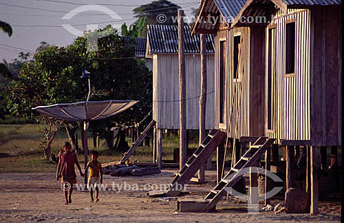  Girl and boy, hands given, in front of wood houses in Paracarica village - Rio Negro (Black River) Amazonas state - Brazil 