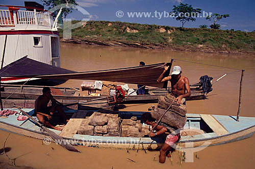  (Hevea brasiliensis) Men in a boat with latex cargo for future production of rubber - Xapuri village - Acre state - Brazil 