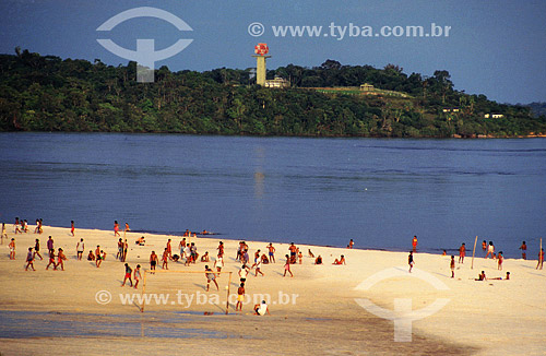  People on the beach of Sao Gabriel da Cachoeira village with the tower of the SIVAM Project - System of Surveillance of the Amazonian in the background - Rio Negro (Black  River) - Amazonas state - Brazil 