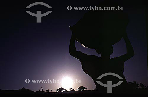  Silhouette of woman (laundress) with basin of clothes on her head and children in the background on Lagoa de Abaeté (Abaete Lagoon) - Salvador city - Bahia state - Brazil 