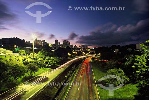  Car passing on road with the city in the background at twilight - Londrina city - Parana state - Brazil - March 2004 