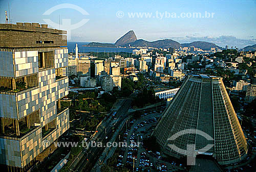  Aerial view of Rio de Janeiro city downtown, showing the conical Cathedral of São Sebastião do Rio de Janeiro (or Metropolitan Cathedral) to the right, the Petrobras and BNDES buildings directly behind the cathedral and Sugar Loaf Mountain* in the b 