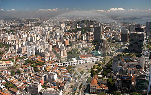  Aerial view of  Rio de Janeiro city downtown, showing the conical São Sebastião do Rio de Janeiro`s Cathedral (or Metropolitan Cathedral), the Petrobras Building (in cubes behind the cathedral) and the BNDES building. To the right one can see the 