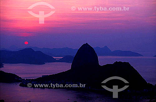  Silhouette of Sugar Loaf Mountain* at daybreak with a red sun in the background - Rio de Janeiro city - Rio de Janeiro state - Brazil  * Commonly called Sugar Loaf Mountain, the entire rock formation also includes Urca Mountain and Sugar Loaf itself 