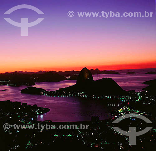  Silhouette of Sugar Loaf Mountain* at sunset with the lights of Botafogo Cove in the foreground - Rio de Janeiro city - Rio de Janeiro state - Brazil  * Commonly called Sugar Loaf Mountain, the entire rock formation also includes Urca Mountain and S 